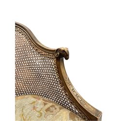 Early 20th century walnut Bergère chair, moulded and shaped frame terminating in rams head, cane woven back meets patterned upholstered seat, raised on leaf carved and fluted supports 