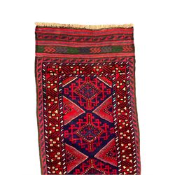 Meshwani crimson ground runner rug, the indigo field decorated with geometric lozenges, guarded border with repeating stylised shapes