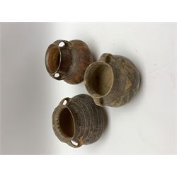 Three Chinese Neolithic pottery vessels, each with twin loop handles to the shoulder and painted geometric banded decoration to the body, all bearing labels for Eskenazi London, tallest H14cm