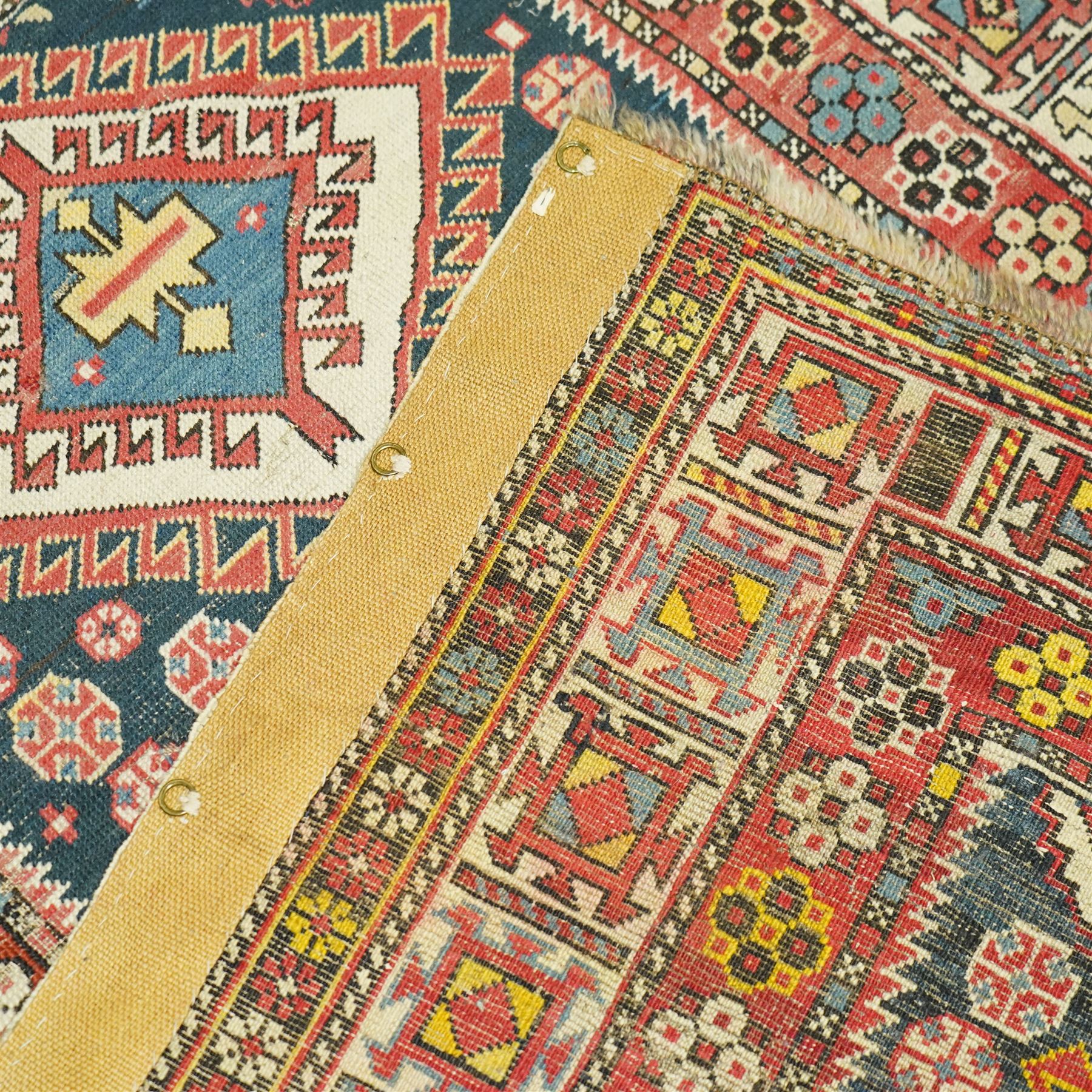 Vintage Caucasian Shirvan hand-knotted rug, indigo field with an arrangement of geometric diamond medallions and stylized tribal motifs within multiple patterned borders, with fringe ends 