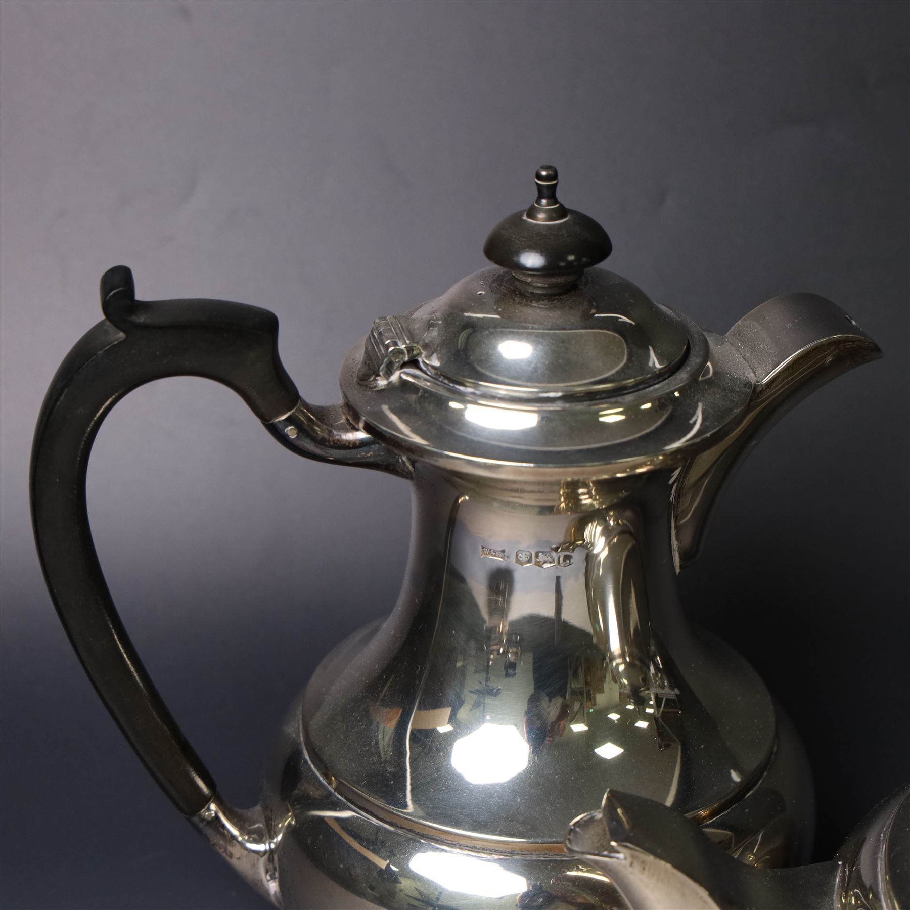 Mid 20th century silver four piece tea service, comprising teapot, hot water pot, open sucrier and milk jug, all of squat bellied form, the teapot and hot water pot with ebonised handles and finials, hallmarked Walker & Hall, Sheffield 1953, hot water pot H19cm