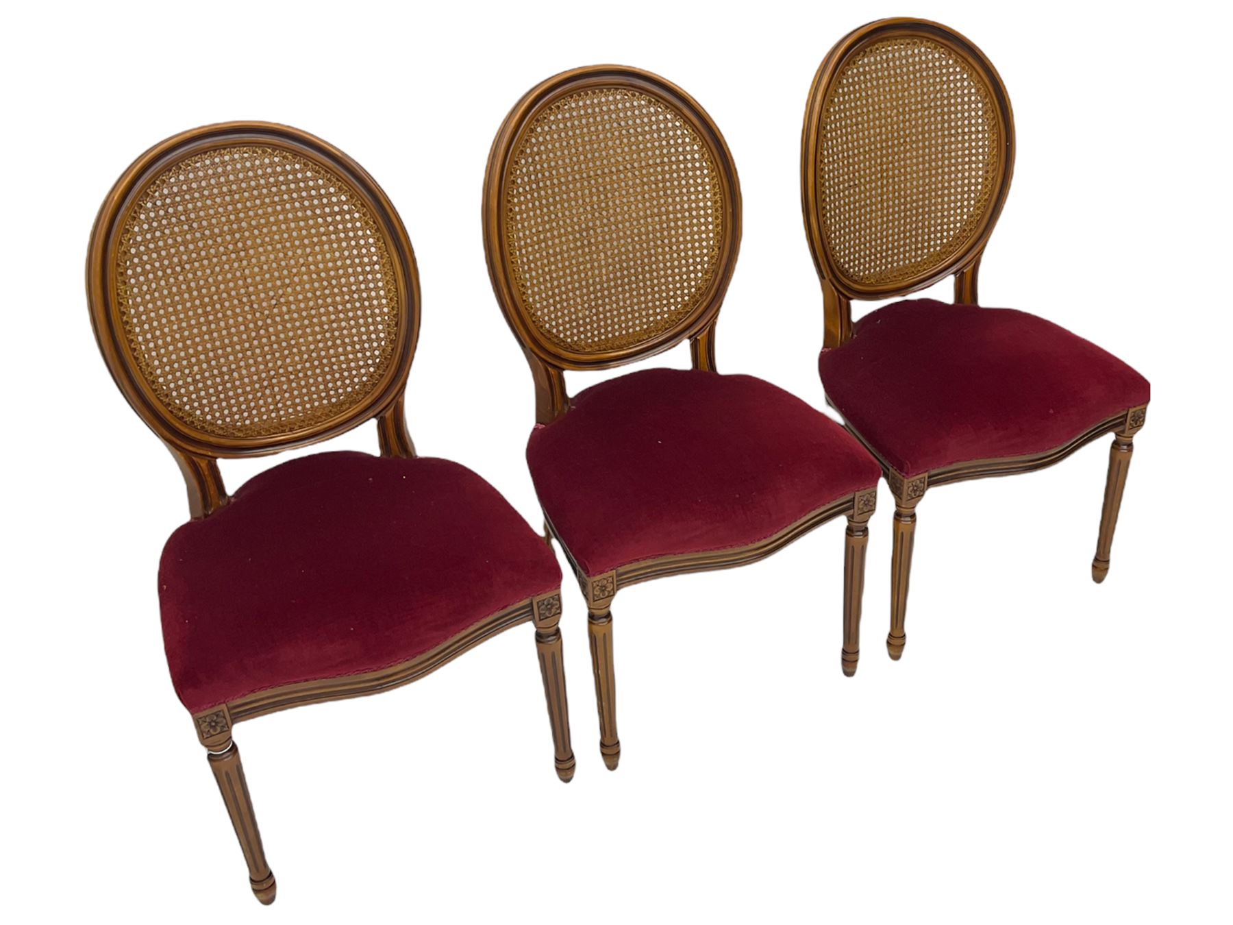 Set six French style walnut finish dining chairs, oval cane bergere backs over serpentine seats upholstered in red, flower head carved fluted supports
