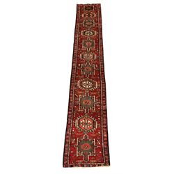 Persian Gharajeh runner, red ground and decorated with multiple medallions, all-over stylised flower head and geometric motif decoration, repeating border 