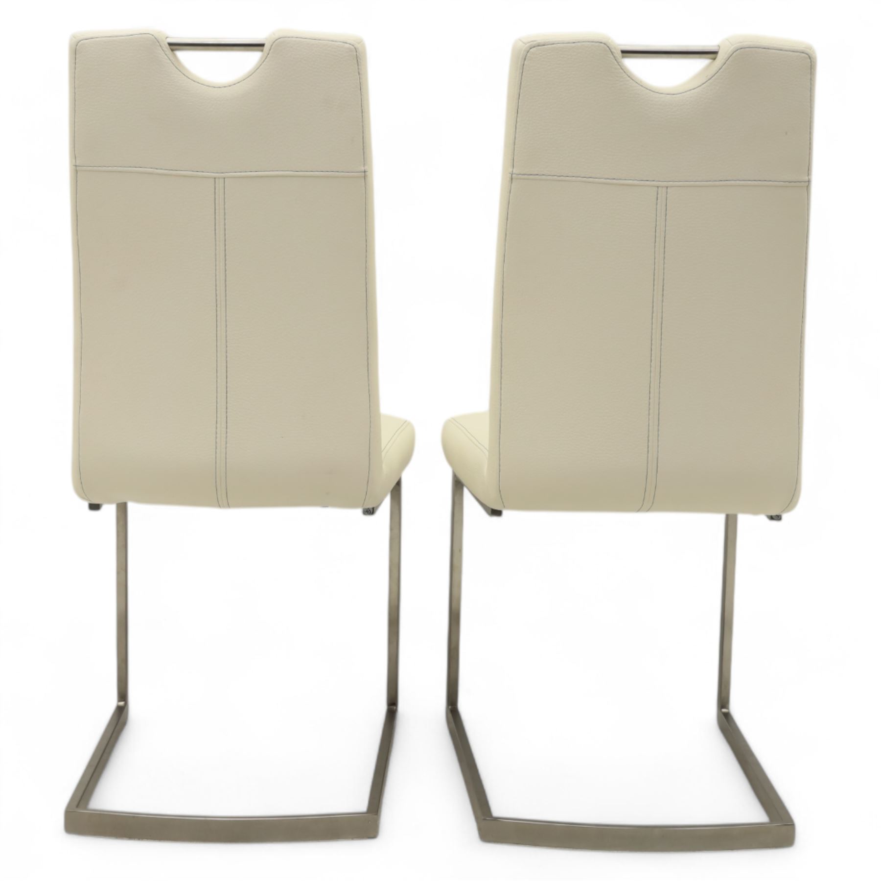 Set of seven contemporary style dining chairs, each with a high padded back and seat upholstered in faux leather on brushed steel sled bases  