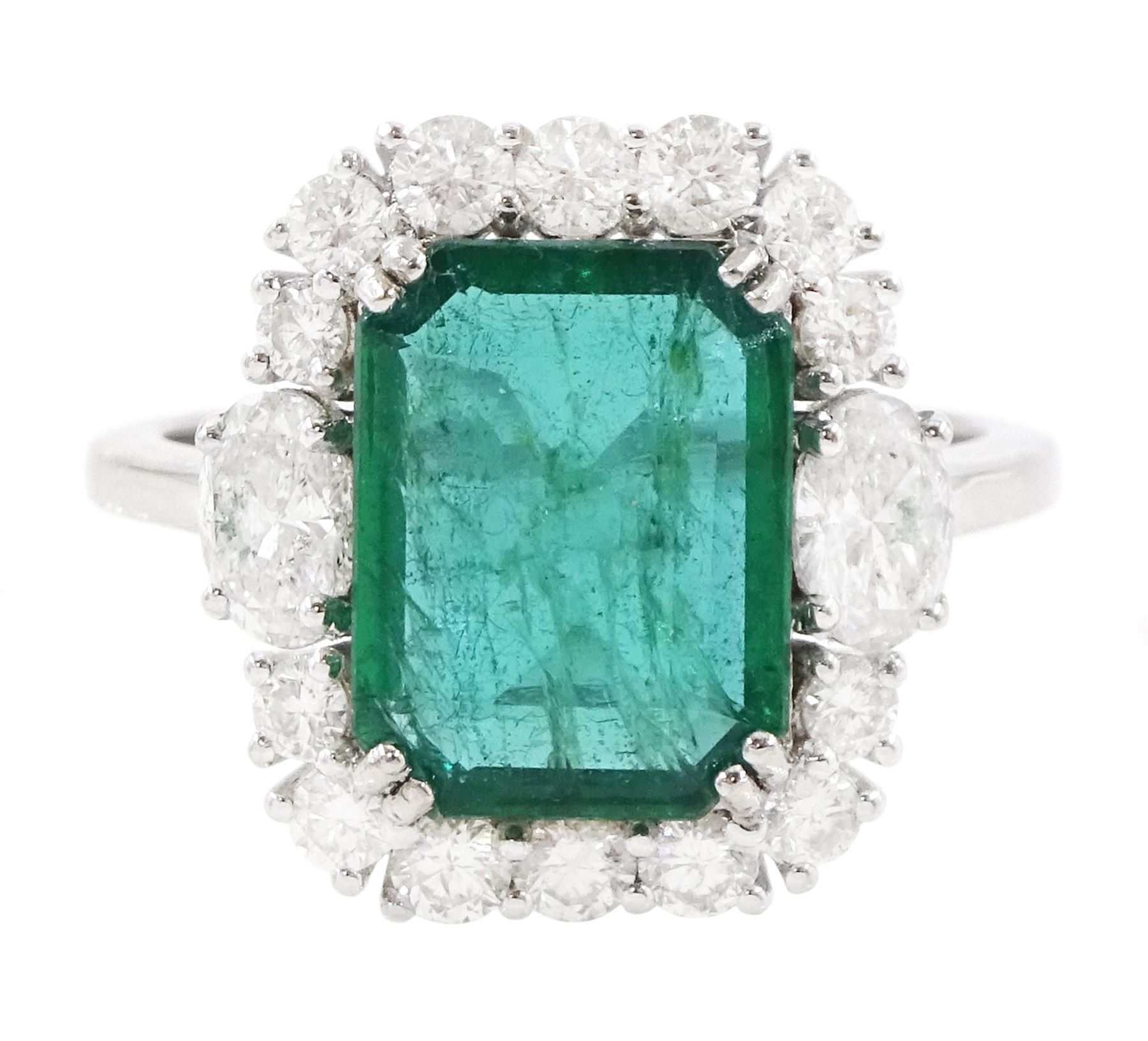 18ct white gold emerald and diamond cluster ring, the octagonal cut emerald of approx 2.85 carat, with an oval cut diamond set either side and round brilliant cut diamond surround, stamped, total diamond weight approx 1.05 carat