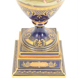 Late 19th century Vienna twin handled urn and cover decorated with classical figures on a textured gilt ground,  upon a square stepped cobalt blue pedestal with gilt detailing, H36cm