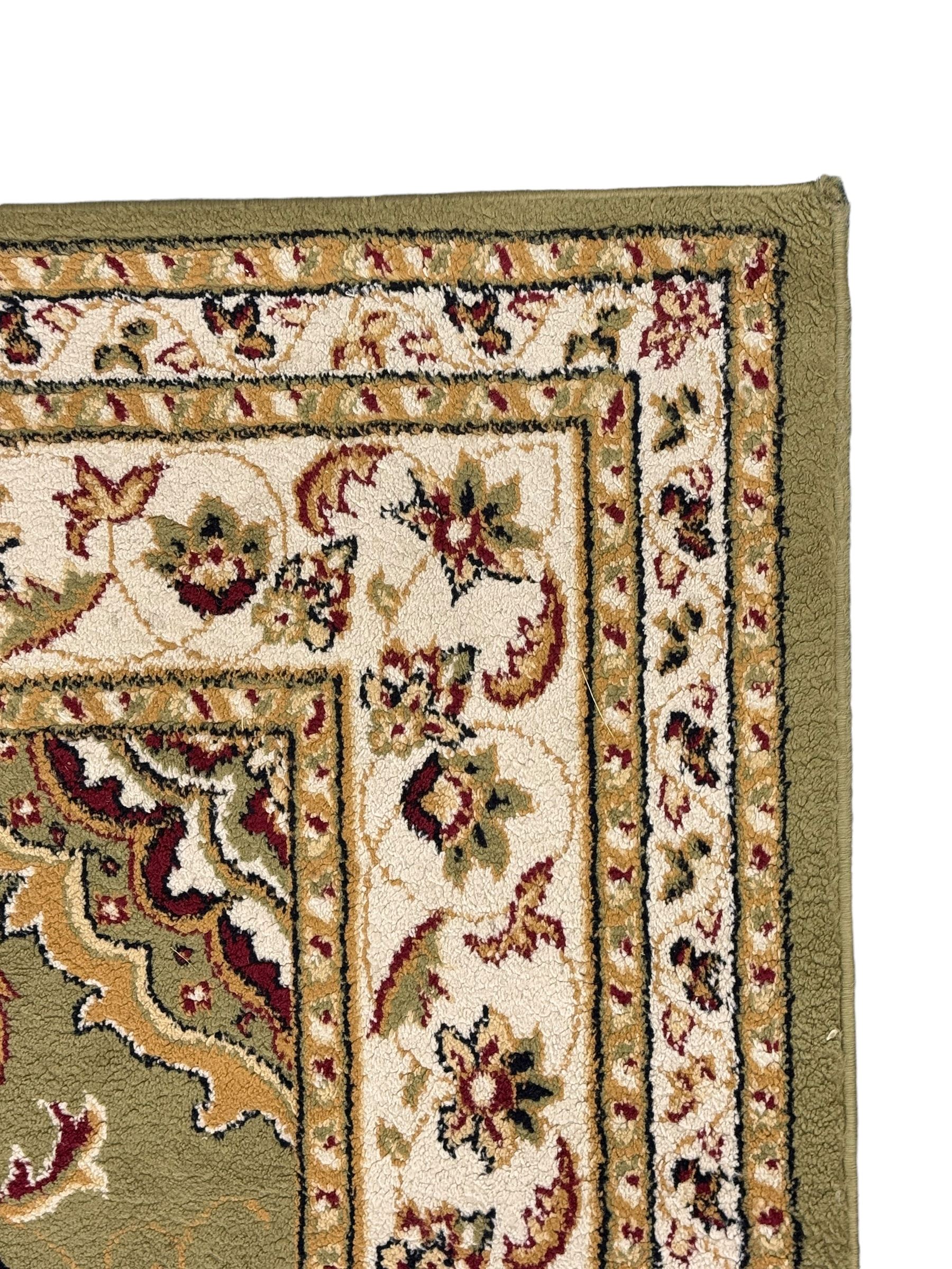 Turkish Sincerity Royale green ground rug, the field decorated with a central floral medallion surrounded by scrolling floral motifs in shades of cream, beige, and burgundy, spandrels filled with matching floral designs, the border featuring a series of floral patterns on a cream ground, finished with green edges