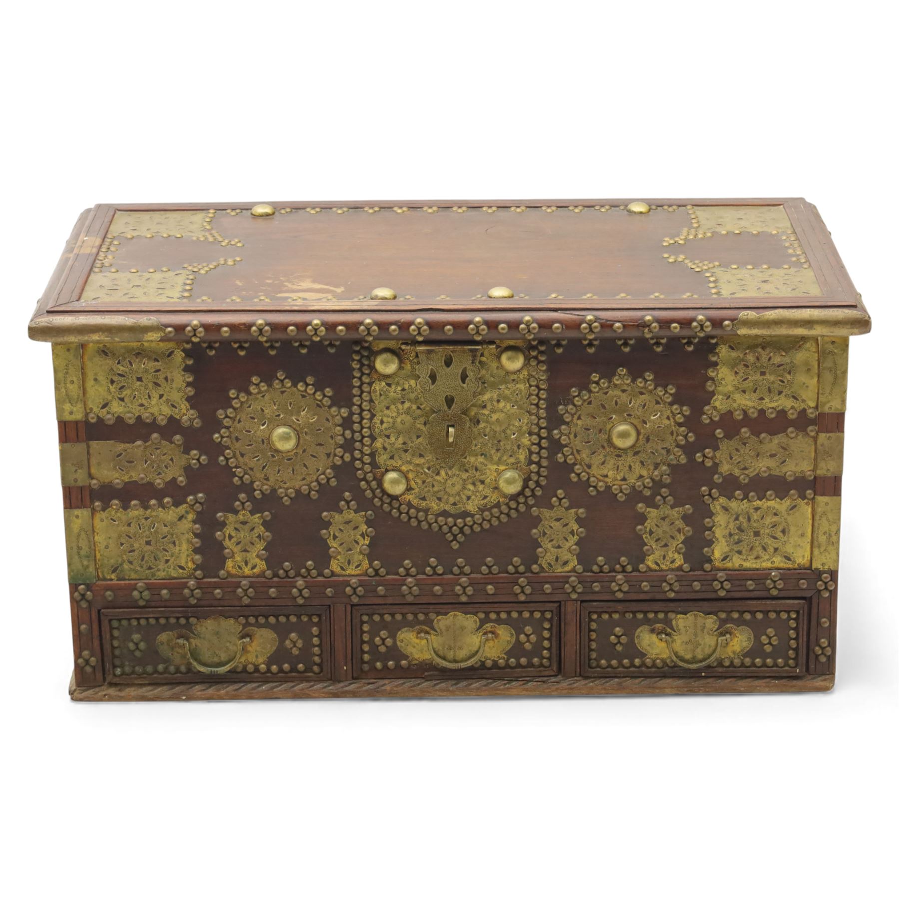 Early 20th century brass-mounted hardwood chest, the hinged top and front richly decorated with applied and studded brass panels and pierced lock escutcheon, revealing a candle box, reinforced with brass corner mounts