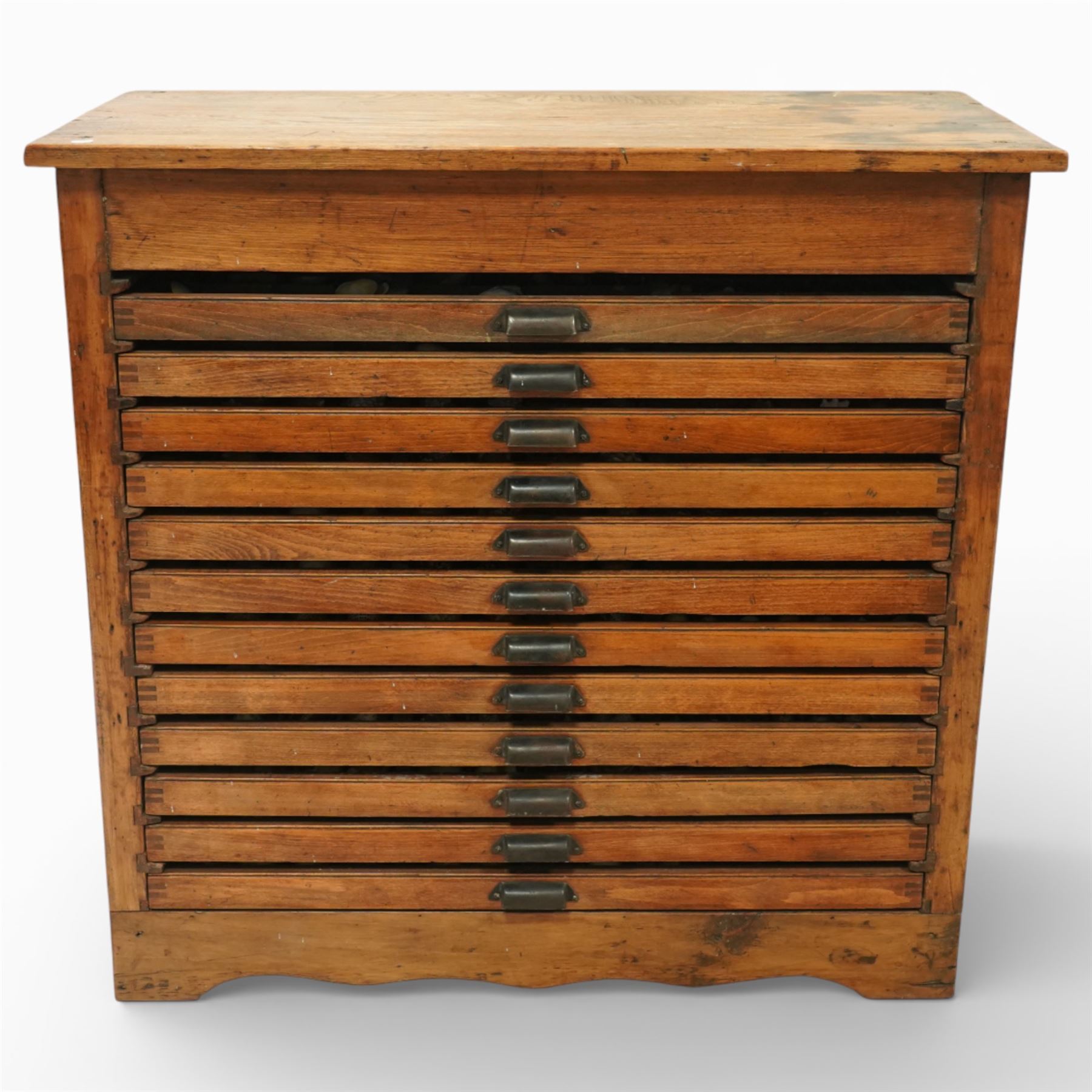 20th century oak printers cabinet, the rectangular top over a bank of twelve shallow drawers each fitted with a metal label handle, the drawers internally compartmentalised and containing an assortment of shells, raised on a shaped plinth base
