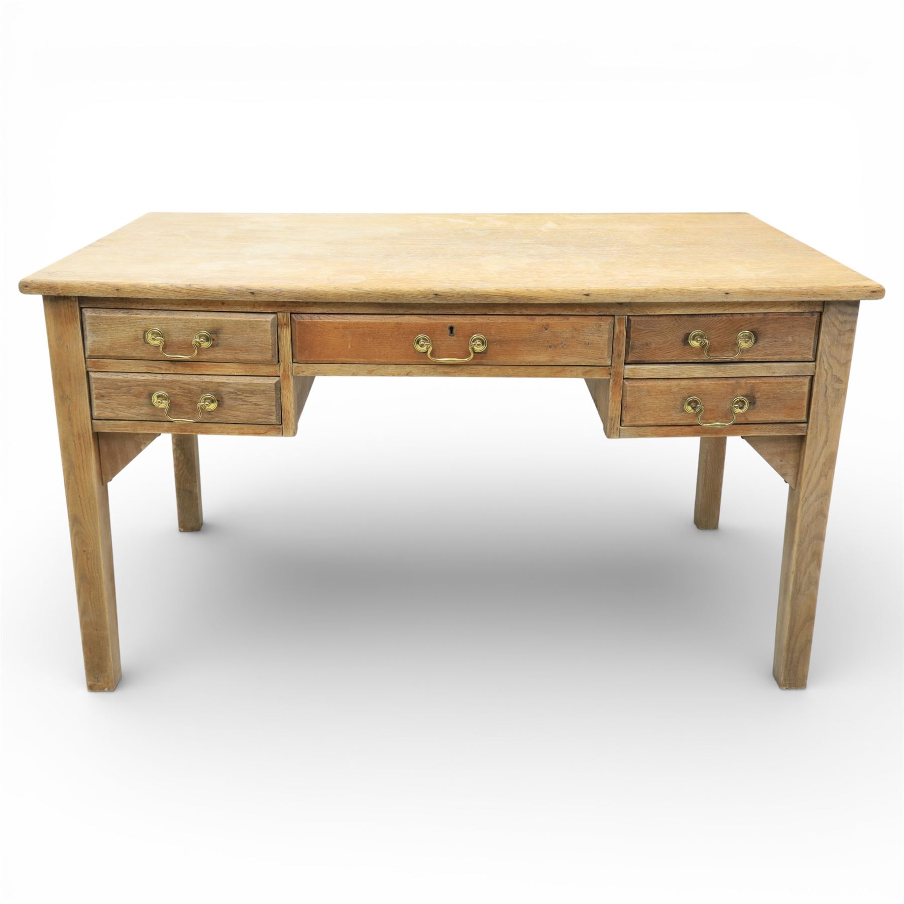 20th century oak kneehole desk, the rectangular top above central drawer and kneehole, flanked by short banks of two drawers, each fitted with brass drop handles, raised upon four plain slightly tapering legs, 75.5cm x 135cm x 73.5cm
