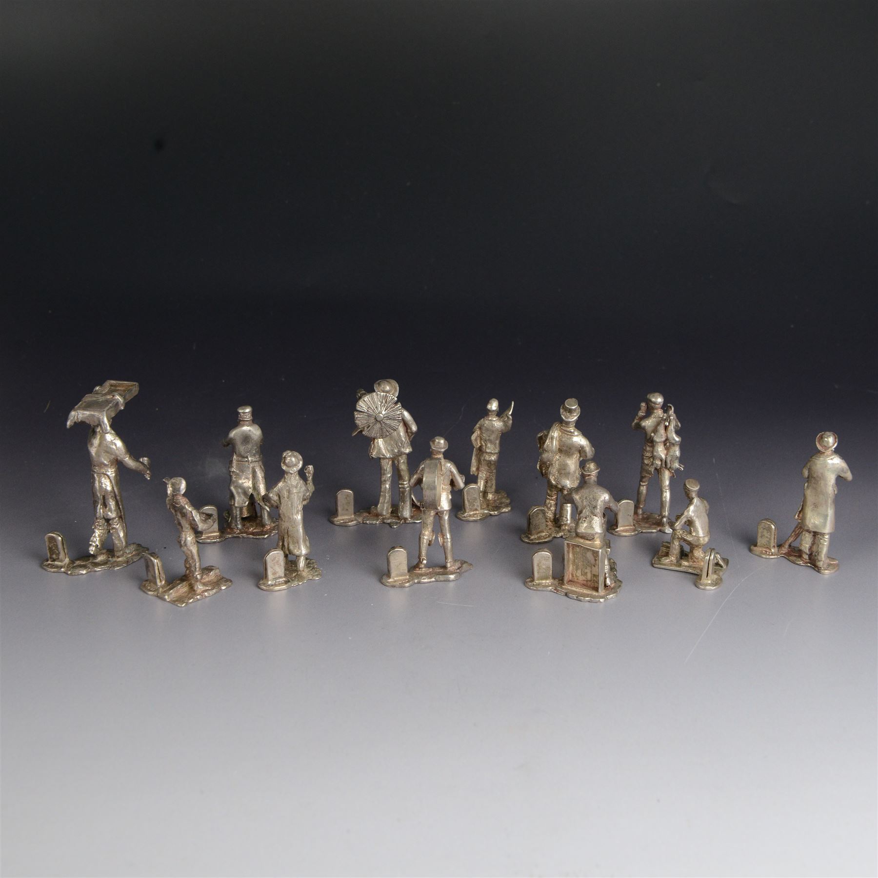Set of twelve silver place card holders from the 'Cries of London' series, each depicting traditional London street traders, hallmarked Thomas Charles Jarvis, London 1975, tallest H6.5cm