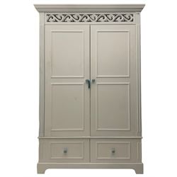 White painted double wardrobe, pierced scrolling foliate frieze over two doors enclosing hanging rail and two shelves, two drawers fitted to base, with blue ceramic handles
