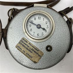 Metal cased drum shaped travelling clock with grey hammered finish, French clockwork movement and stitched leather outer case with shoulder strap; bears manuscript label 'Royal Armament Research and Development Establishment - serial no.09433' D13cm overall