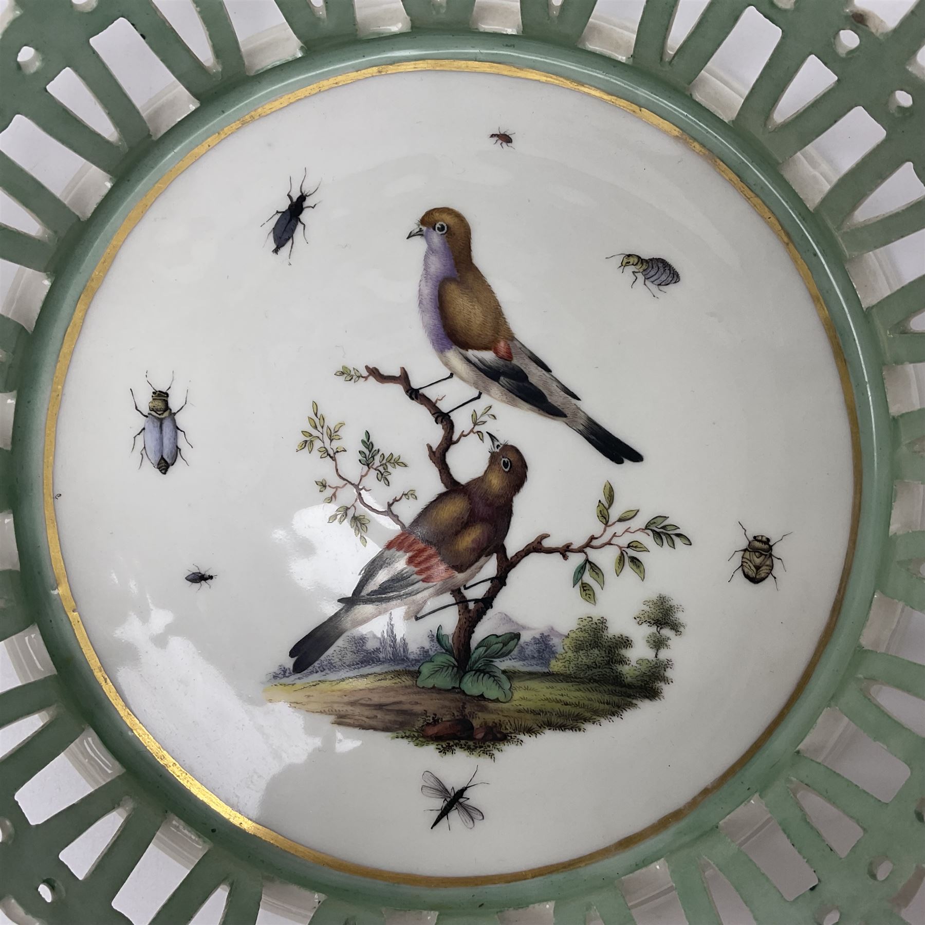 Pair of 19th century German openwork chestnut baskets, with twin handles and scrolling gilt border and star rim, painted to the centre with birds and insects, D22cm 