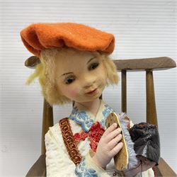 Anna Meszaros Hungary - three hand made needlework figurines - 'The Cobbler' as a child seated in a wooden rocking chair working on a removed boot H24cm; young girl standing crying holding a doll with broken head H32cm; and young girl in long dress and bonnet standing holding a doll H27cm (3)  Auctioneer's Note: Anna Meszaros came to England from her native Hungary in 1959 to marry an English businessman she met while demonstrating her art at the 1958 Brussels Exhibition. Shortly before she left for England she was awarded the title of Folk Artist Master by the Hungarian Government. Anna was a gifted painter of mainly portraits and sculptress before starting to make her figurines which are completely hand made and unique, each with a character and expression of its own. The hands, feet and face are sculptured by layering the material and pulling the features into place with needle and thread. She died in Hull in 1998.