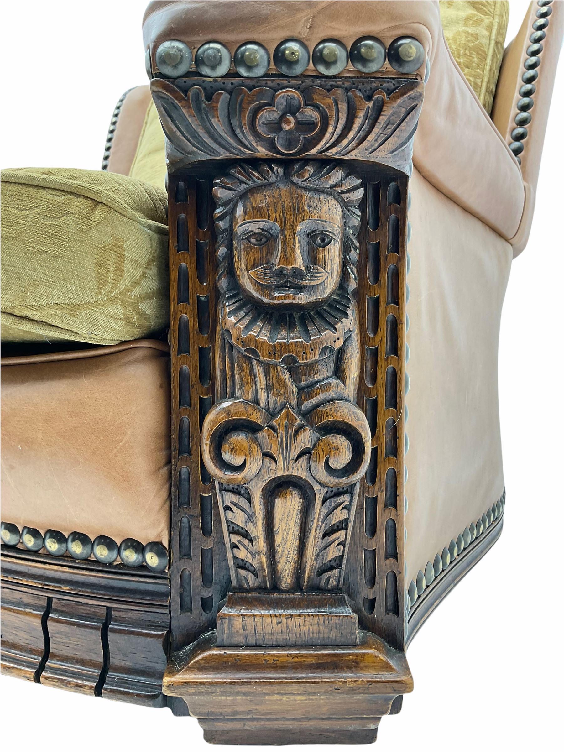 Pair of 1930’s carved oak framed club chairs, upholstered in tan studded leather with beige fabric loose cushions