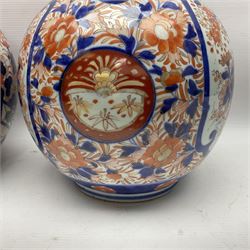 Pair of large 19th century Japanese Imari porcelain bottle vases, painted with shaped reserves of peonies, chrysanthemums and prunus blossom, each H46cm