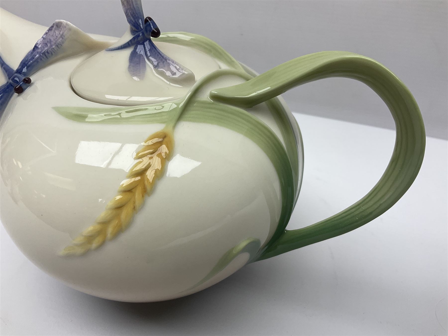 Franz Teapot decorated with dragonflies, together with a matching sucrier and cover and a cup and saucer in Iris pattern, all with printed mark beneath 