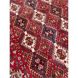 Persian Shiraz rug, red ground and decorated with three bands of stepped lozenge medallions, decorated with small geometric and stylised motifs, the border with repeating geometric design