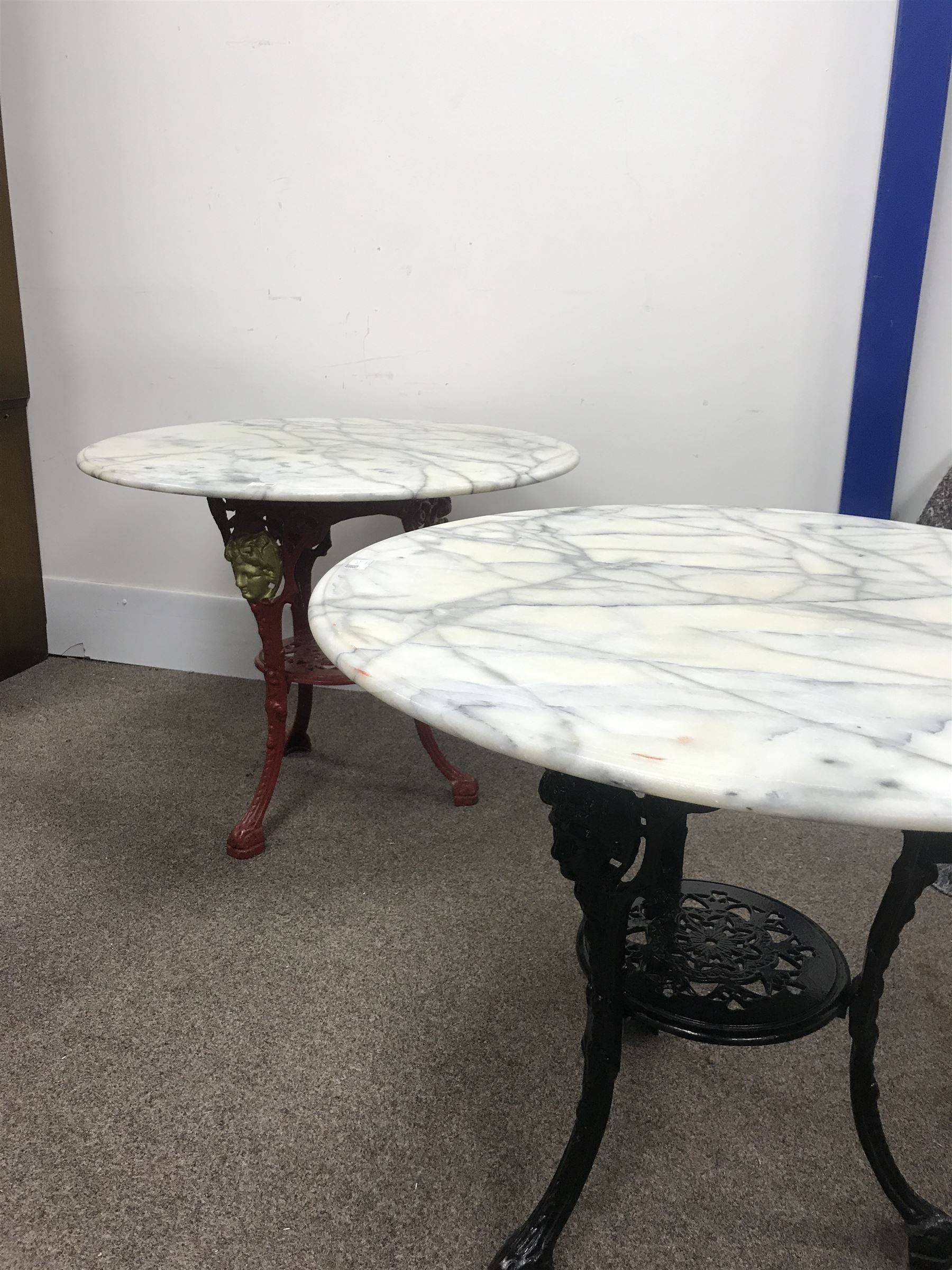 Pair cast iron Britannia pub tables, one red, one black with large marble tops 