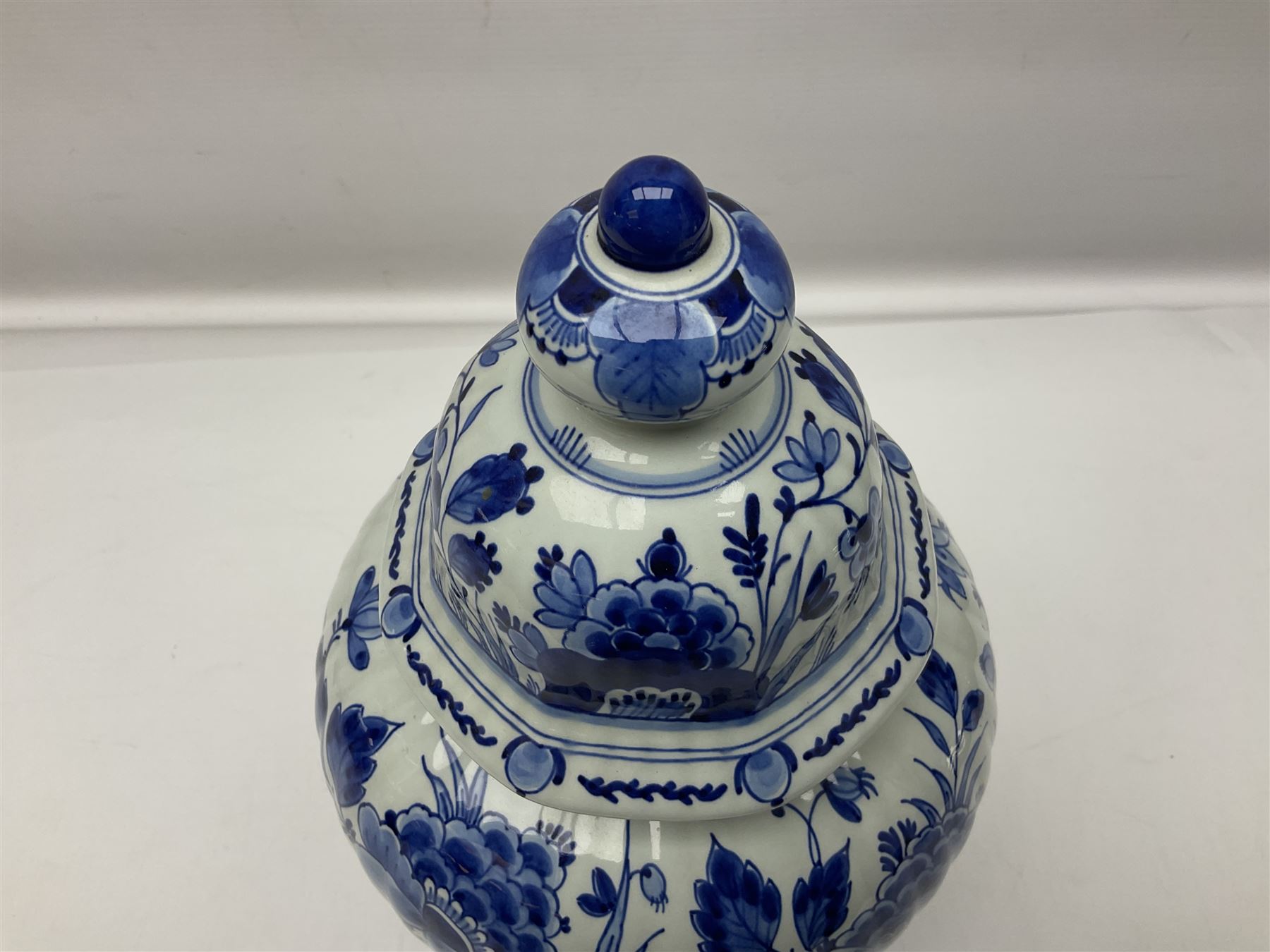 De Porceleyne Fles Delftware blue and white covered jar, of fluted baluster form, with floral and insect decoration, upon an octagonal foot, the octagonal cover with urn shaped finial, H32cm