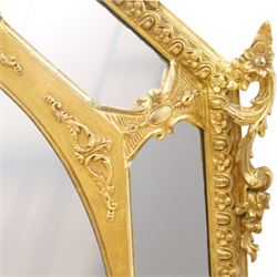 Late 19th century French giltwood and gesso wall hanging cushion mirror, the pierced foliate rocaille pediment extending acanthi C-scrolls and trailing bellflowers, over a floral garland and cartouche moulded rails, the central oval bevelled plate surrounded by further bevelled cushion mirrors, with out-scrolling pierced motifs flanking the floral egg-and-dart moulded outer edge, over a pierced foliate cartouche terminal