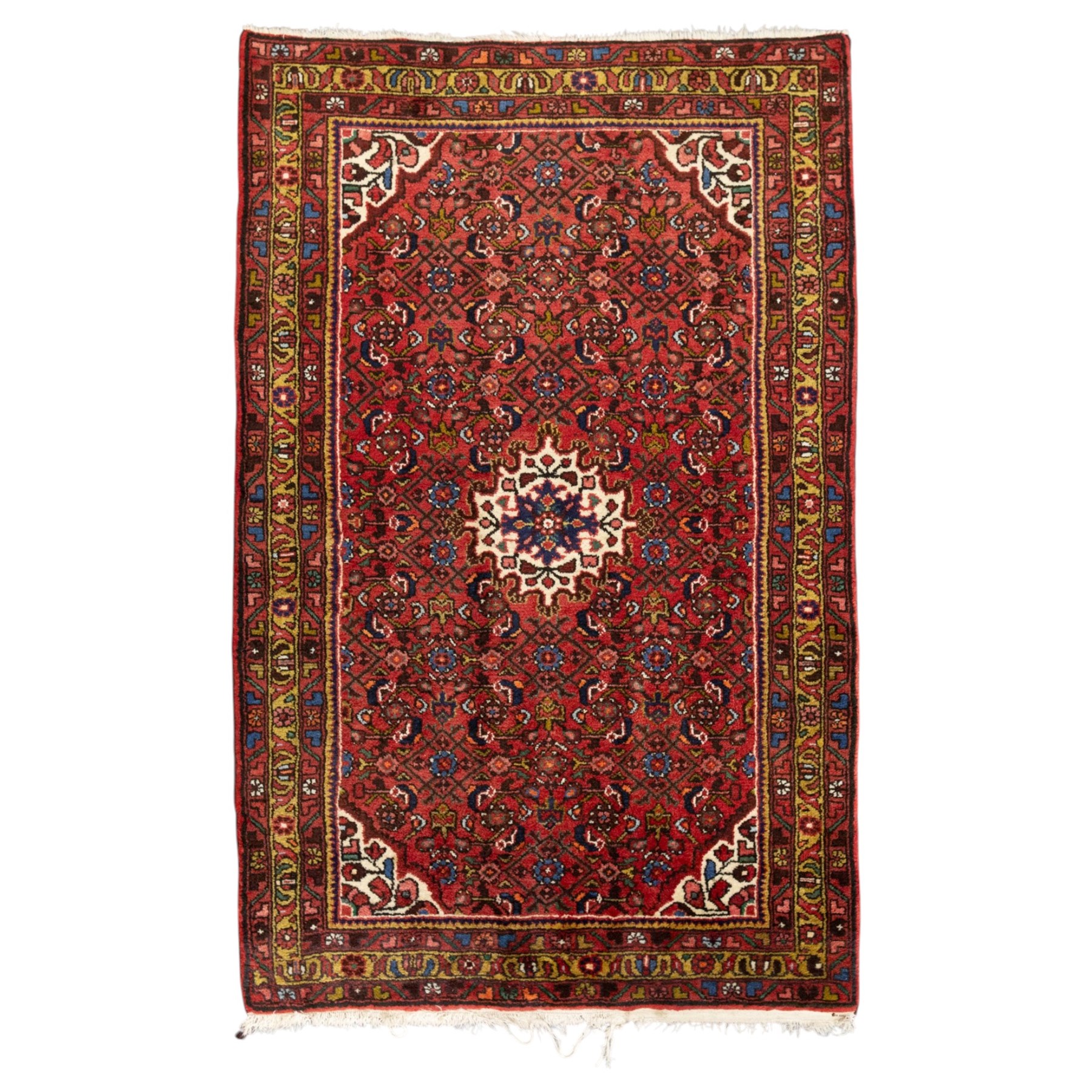 Hamadan hand-knotted rug, red field with small central floral medallion and dense repeating geometric motifs in dark blue, cream and green tones, within multiple patterned borders
