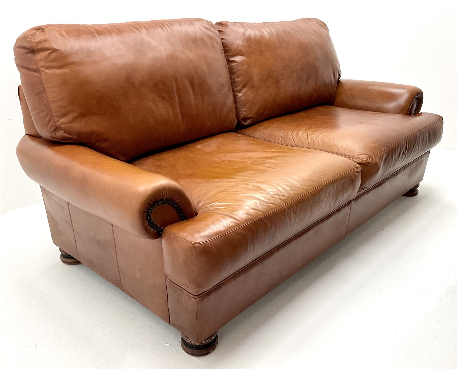 Three seat studded tan leather sofa, scrolling arms, turned supports (W190cm) with matching two seat (W155cm) armchair (W100cm) and footstool 