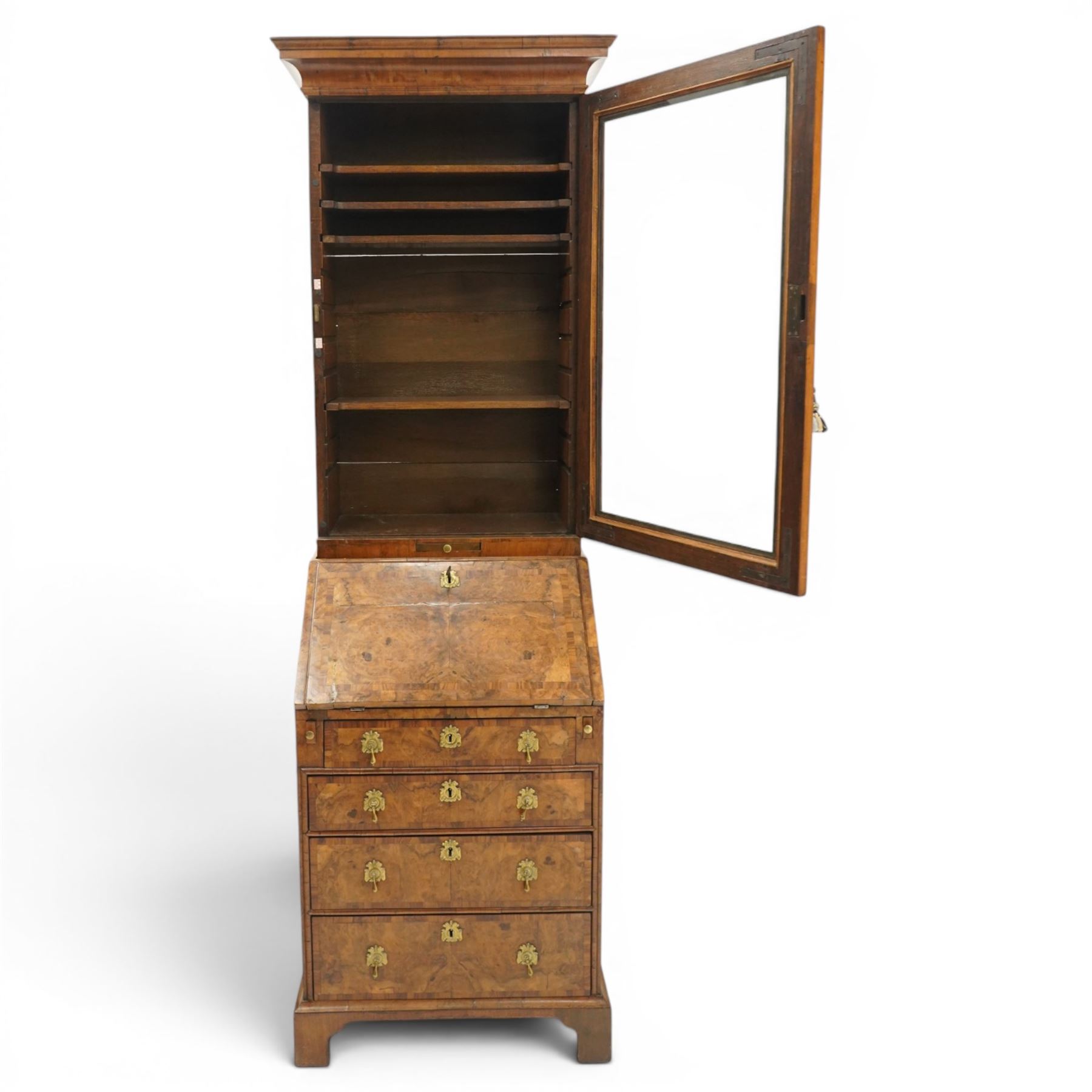 Quality George I figured and burr walnut bureau-cabinet of unusually small proportions, the projecting cavetto cornice over a glazed and banded door enclosing four adjustable shelves, with a candle slide below, the book-matched and banded veneer fall-front enclosing a fitted interior with pigeonholes, correspondence drawers and original trinket boxes and inkwells, over two pull-out stays and four graduating long drawers with banded facias and pressed brass escutcheons and pull handles, lower moulded edge on bracket feet
Provenance: purchased Sotherby's 1977