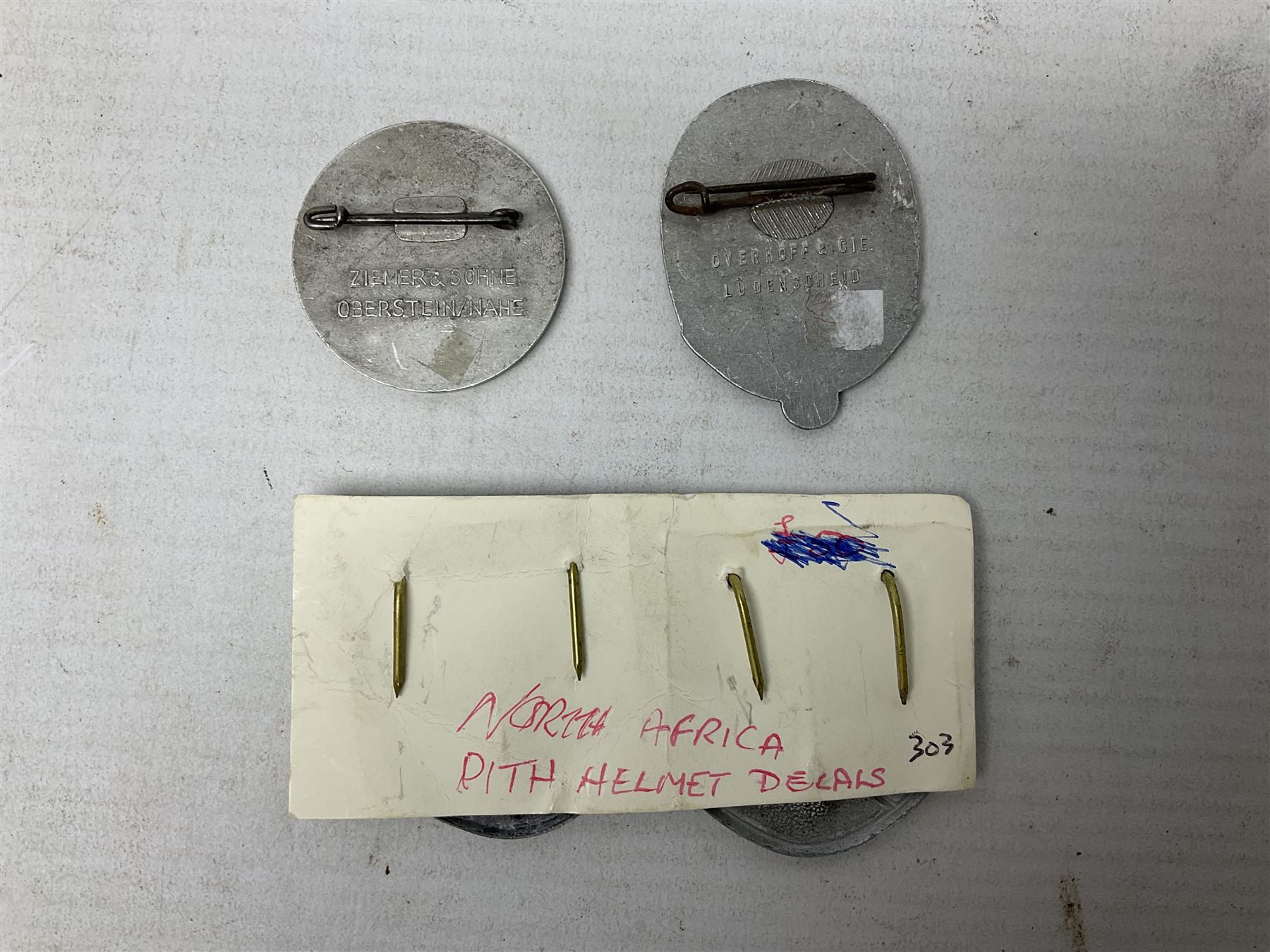 Two WW2 German 'tinnie' badges - Labour Day 1935 by Overhoff & Cie Ludenscheid & Labour Day 1936 by Ziemer & Sohne Oberstein/Nahe; together with pair of Afrika Korps tropical (pith) helmet metal decals (4)