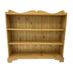Waxed pine bookcase, shaped pediment over four tiers, on bracket feet