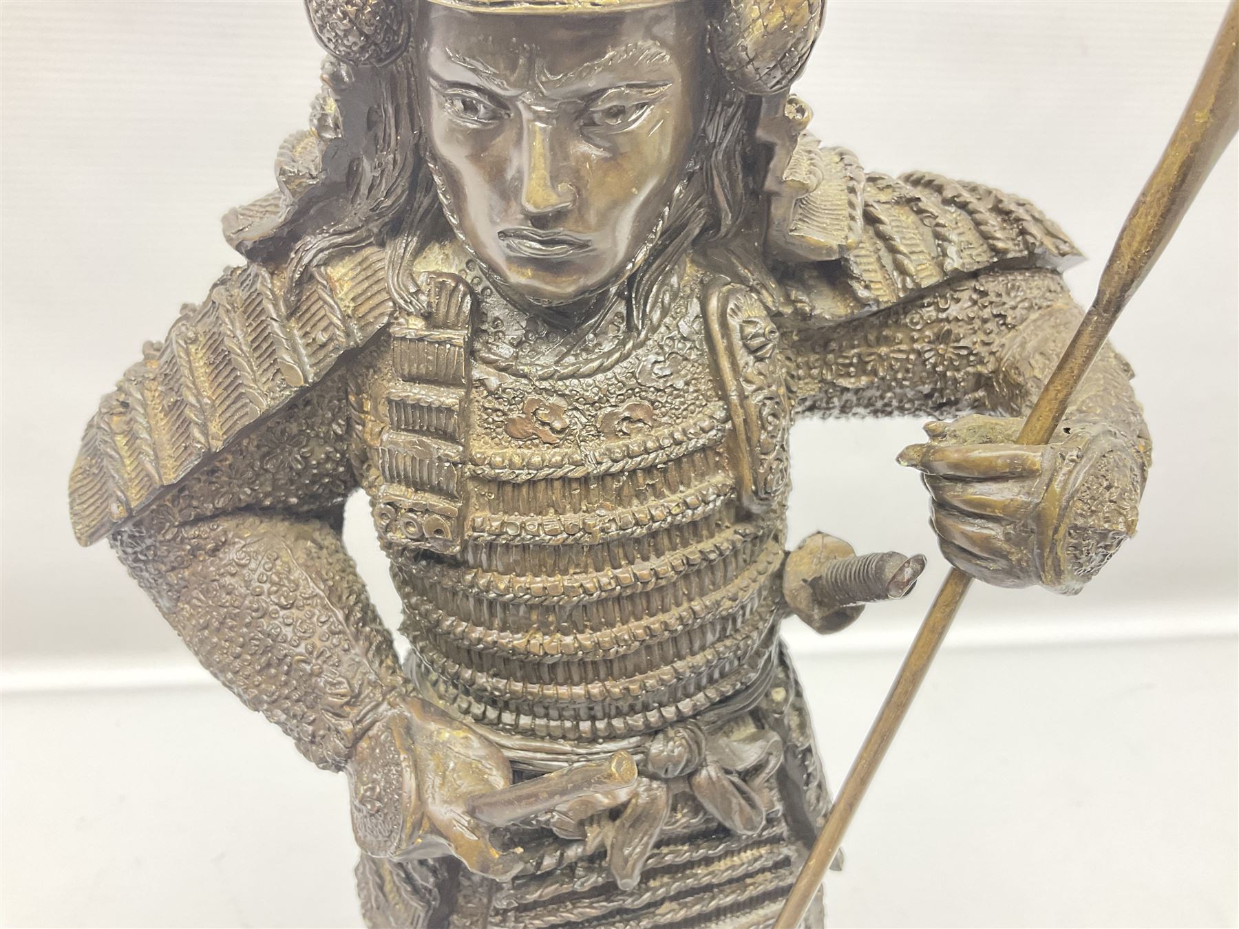 Bronze figure of a samurai standing wearing armour and holding a naginata, upon a rocky base, H48cm