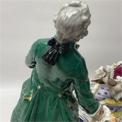 20th century Naples figure group, modelled as a seated female figure playing the lute seated, before a male figure stood holding a sheet of music, each in period dress, upon an oval base with gilt heightened scroll edge, with crowned N mark beneath, H31.5cm L33cm
