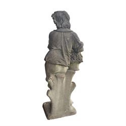 Haddonstone - weathered cast stone garden statue of a boy holding a basket of grapes, modelled with curled locks of hair wearing a tunic and breeches leaning against a naturalistic tree stump, on square base