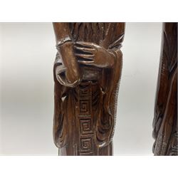 Two large hardwood Oriental figures carved as a man and woman donning robes upon naturalistic plinths