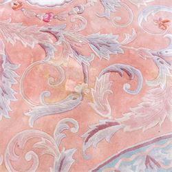 Large late 20th century Aubusson style wool carpet, peach and pastel toned field with central floral medallion enclosing scrolling acanthus and and foliate sprays, surrounding field decorated with further stylized foliage and and floral ornament, within shaped reserves and indigo corner spandrels, enclosed by narrow guard border, cotton fringe ends