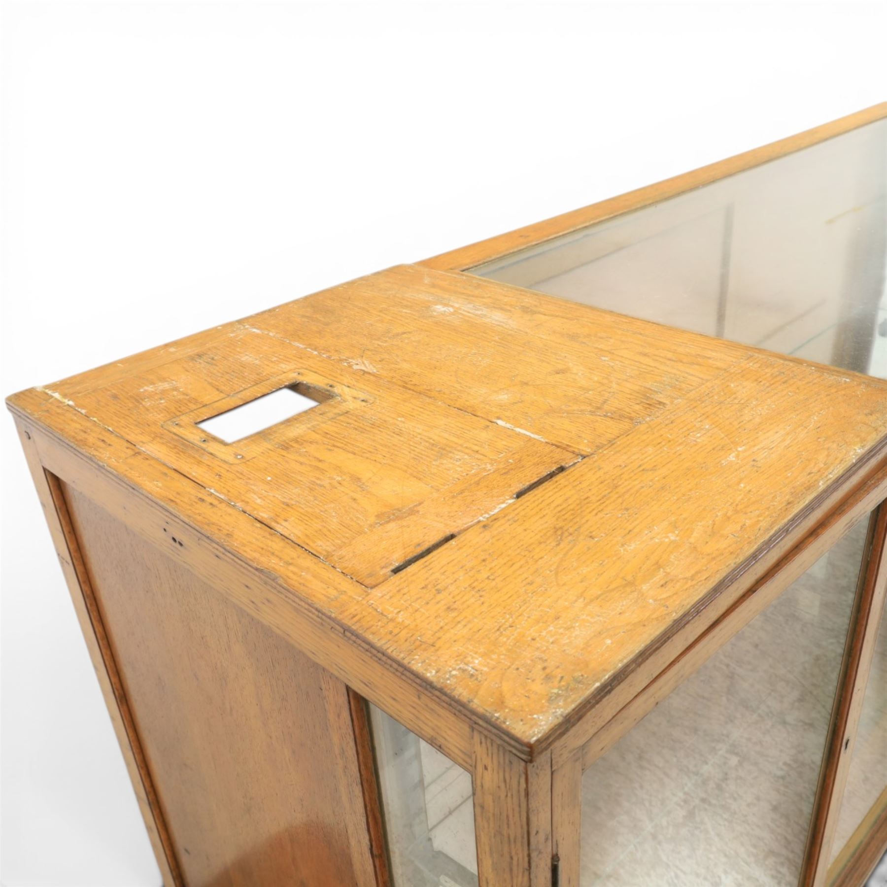 Early 20th century oak framed and glazed haberdashery shop counter with sliding doors and cupboards