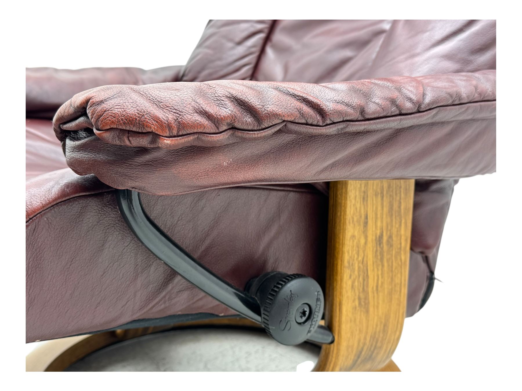 Ekornes Stressless, swivel armchair upholstered in red leather, with matching footstool supported on Oak bases