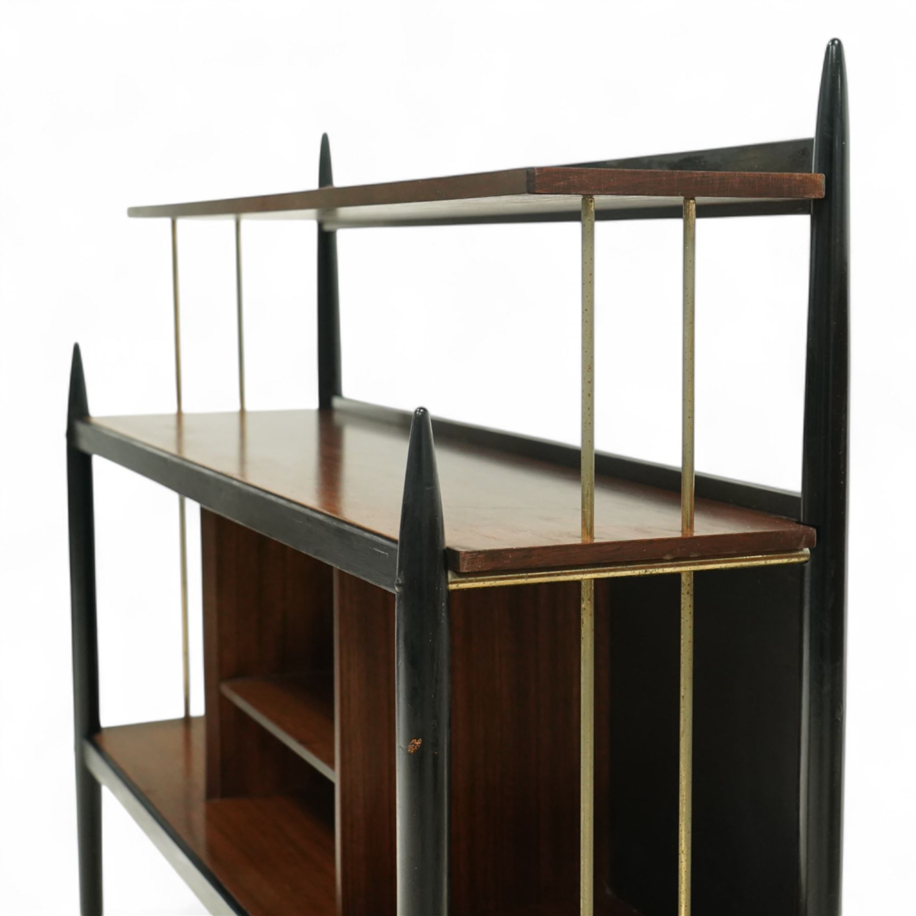 E Gomme for G Plan - 'Librenza' mid-20th century teak and ebonized wood bookcase, rectangular three-tier open shelf design with finials, narrow and raised top shelf above full span and depth central shelf, above divided shelf with open pigeonholes, sides with brass rods, raised on tapering legs with brass capped feet