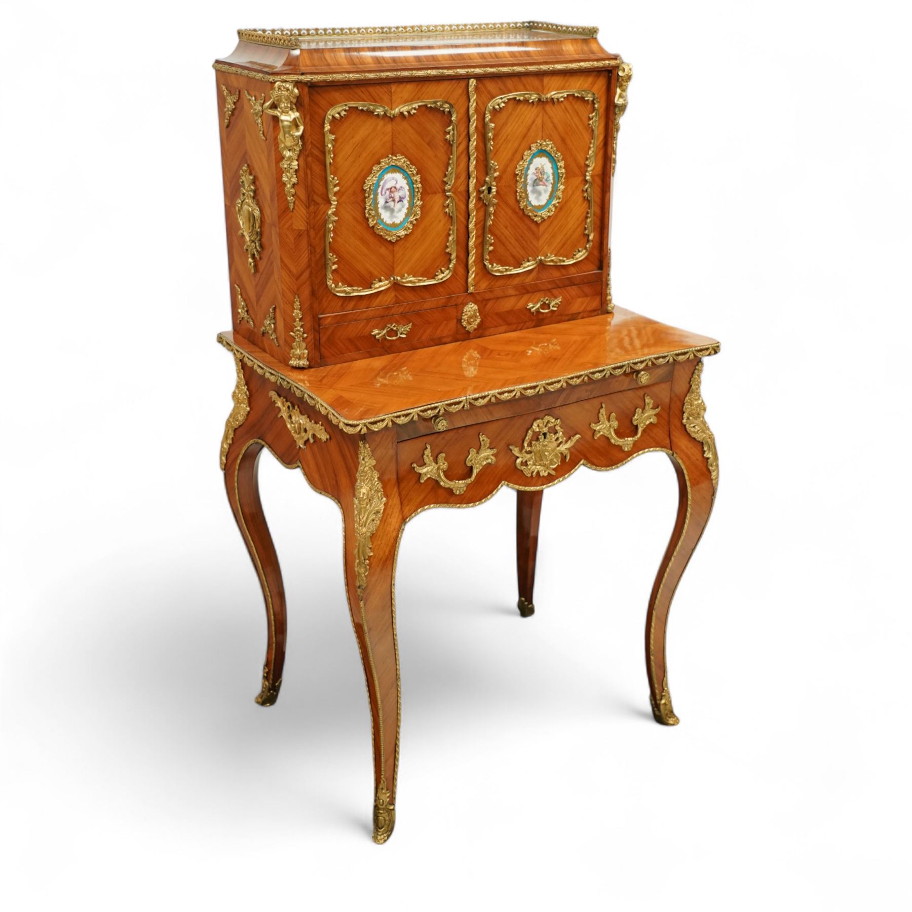 Late 19th century French Louis XV style kingwood and ormolu mounted bonheur du jour, the upper section with a pierced three-quarter gallery over a pair of cupboard doors inset with Sèvres-style porcelain portrait plaques, enclosing a shelved interior over two short drawers, the serpentine top and apron richly mounted with gilt-bronze foliate and scroll motifs, single frieze drawer below on cabriole supports with acanthus cast sabots