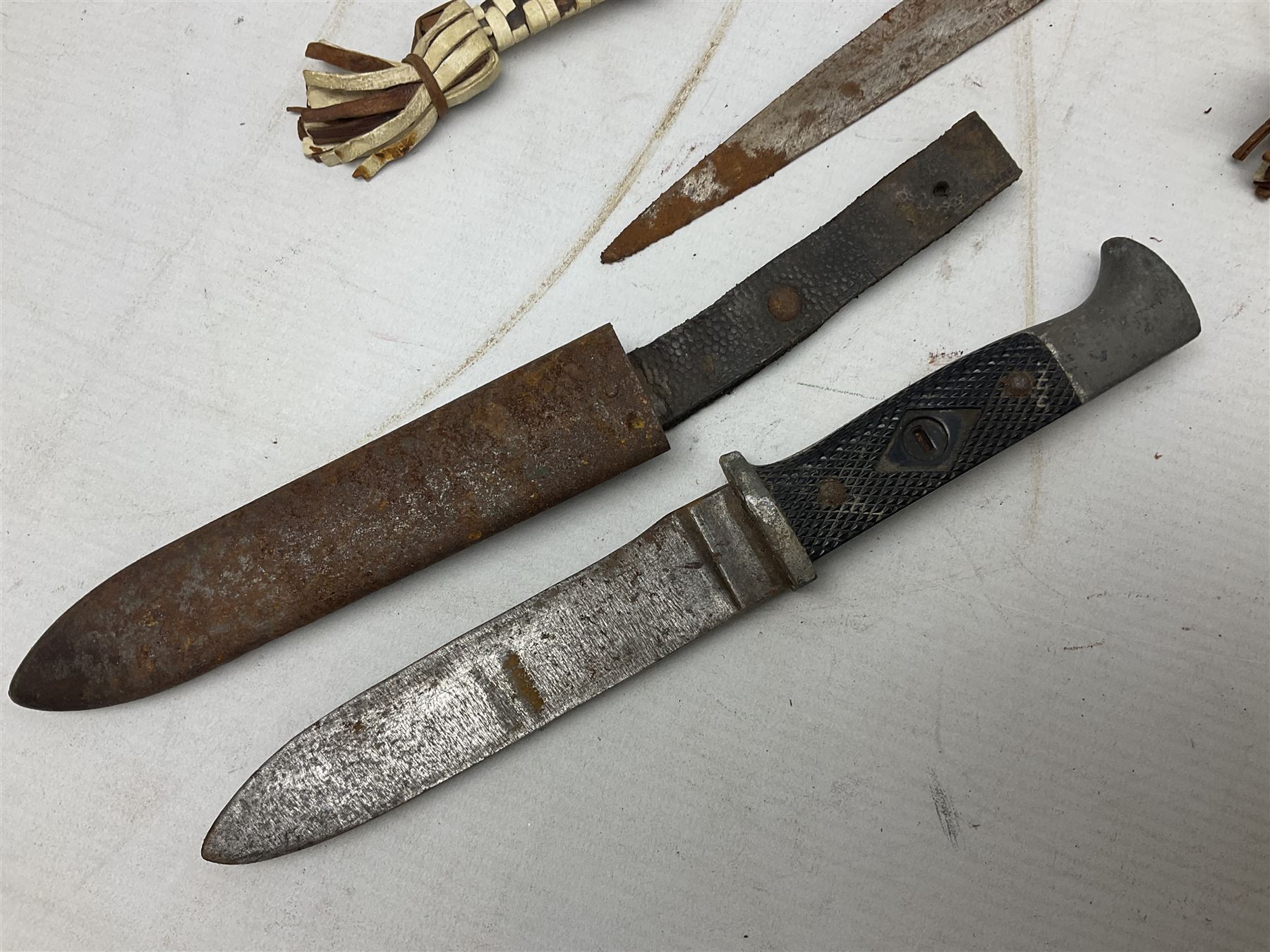 Indian kukri with 29cm curving steel blade and nickel mounted horn grip; in leather covered scabbard with one skinning knife L42cm overall; Hitler Youth knife with scabbard in relic condition; and three African graduated knives each with crudely carved wooden grips and painted leather covered scabbards (5)