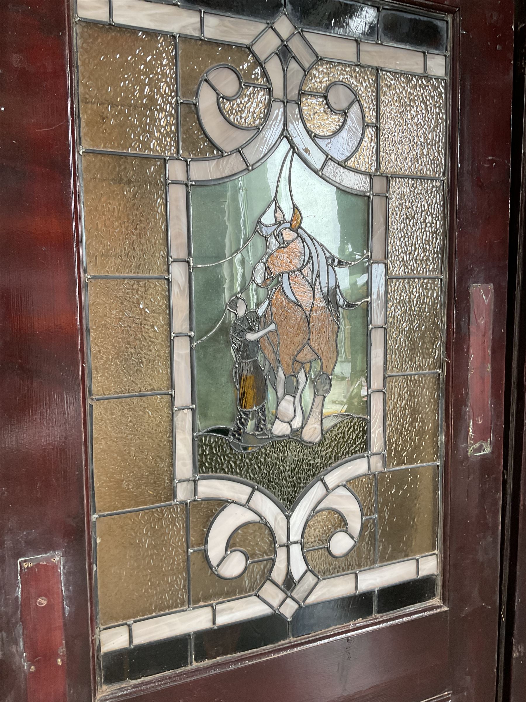 Two early to mid 20th century timber doors, set with lead framed stained glass panels depicting agricultural worker and horse