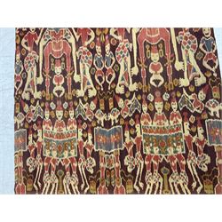 Ikat Man’s Cloth (Hinggi Kombu), East Sumba, Indonesia, woven in red, blue and yellow-brown warp ikat, constructed of two mirroring long panels, the motifs arranged in four bands depicting warrior figures astride rearing horses, high-ranking figures and guardians within geometric borders, on carved wooden wall hanger, L295cm
