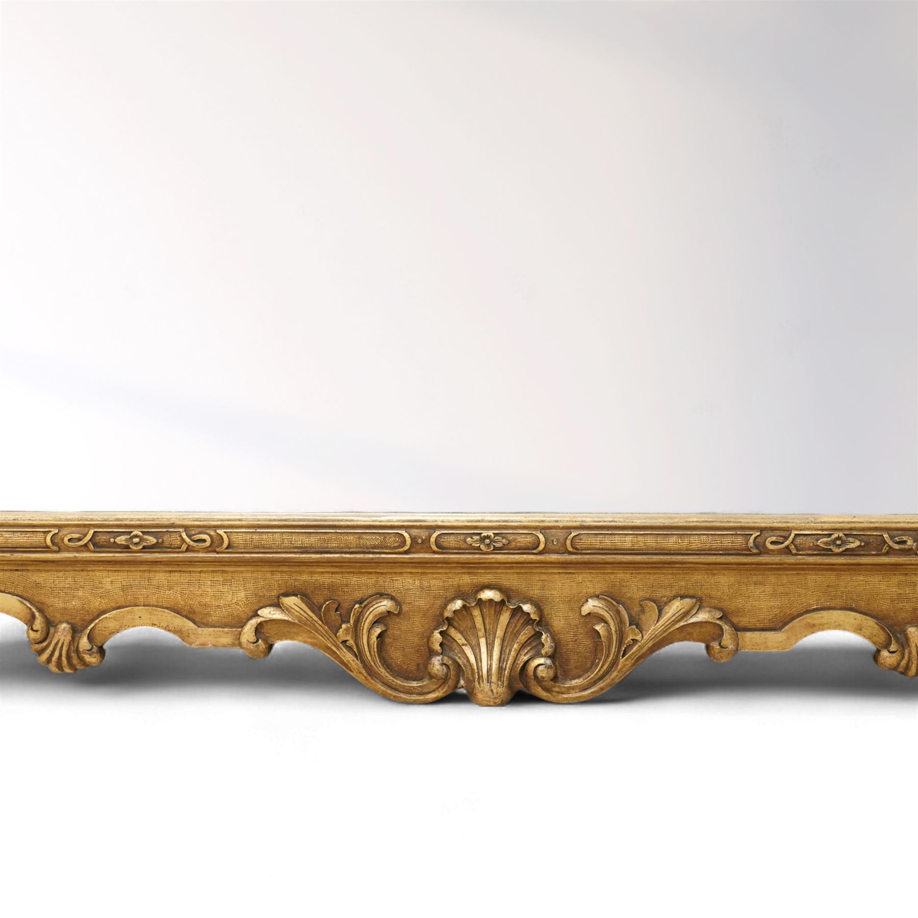 Georgian design giltwood overmantel mirror, arched rectangular plate within a moulded frame, the cresting carved with scrolling acanthus and shell motifs, trailing foliate decoration continuing to the shoulders and lower apron