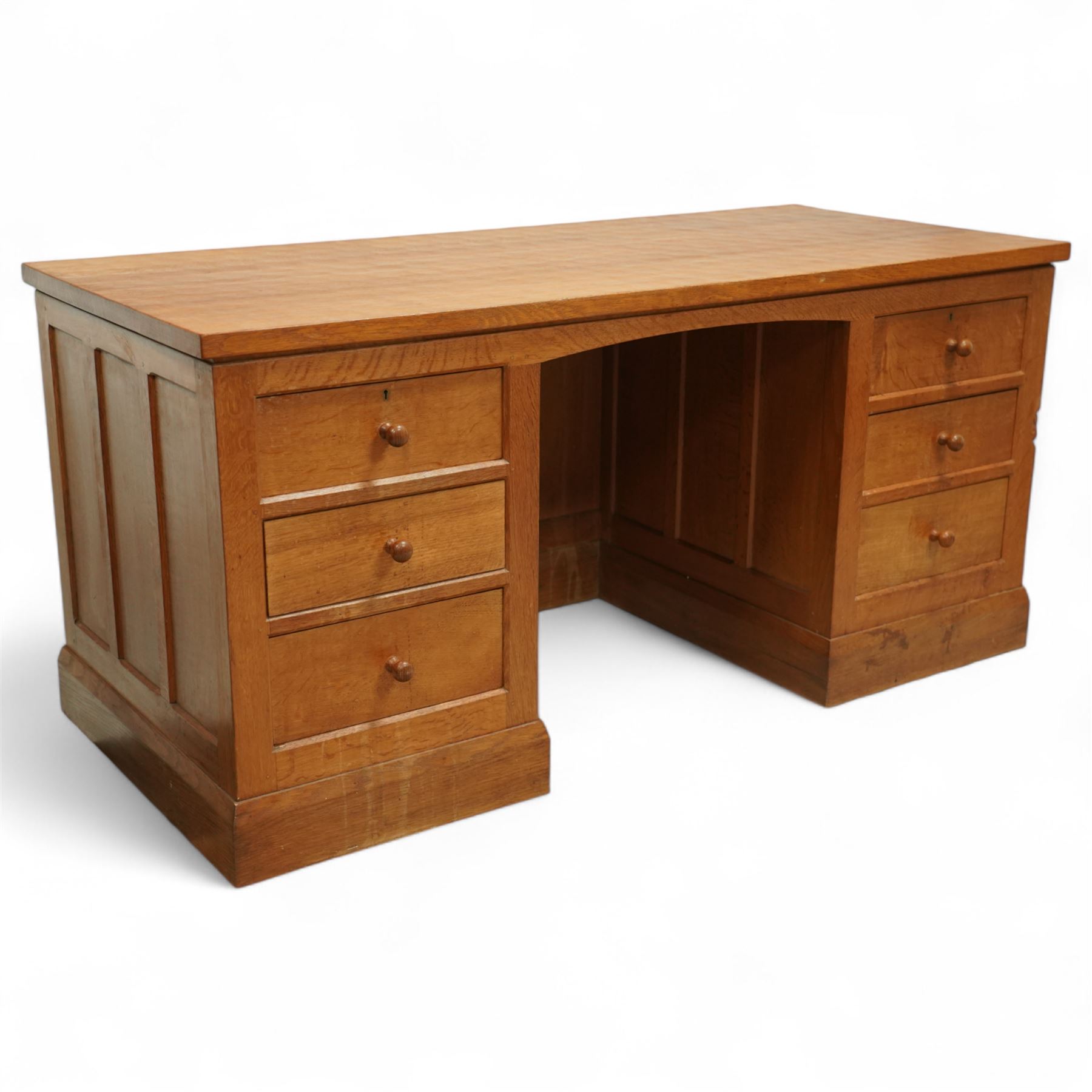 Mouseman - oak pedestal kneehole desk, adzed rectangular top over twin pedestals each fitted with three drawers, arched kneehole with panelled interior, on plinth base, signature carved mouse to side, by the workshop of Robert Thompson, Kilburn