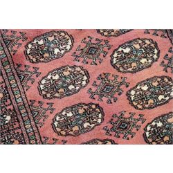 Afghan pale red ground runner, the field decorated with two rows of Gul motifs, within repeating patterned border