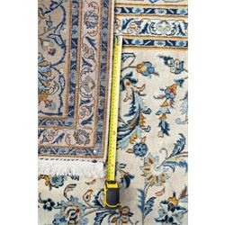 Central Persian Kashan hand-knotted carpet, ivory field profusely decorated with an all-over scrolling vine, palmette, and lotus design in shades of soft blue, pale gold, and green within floral borders