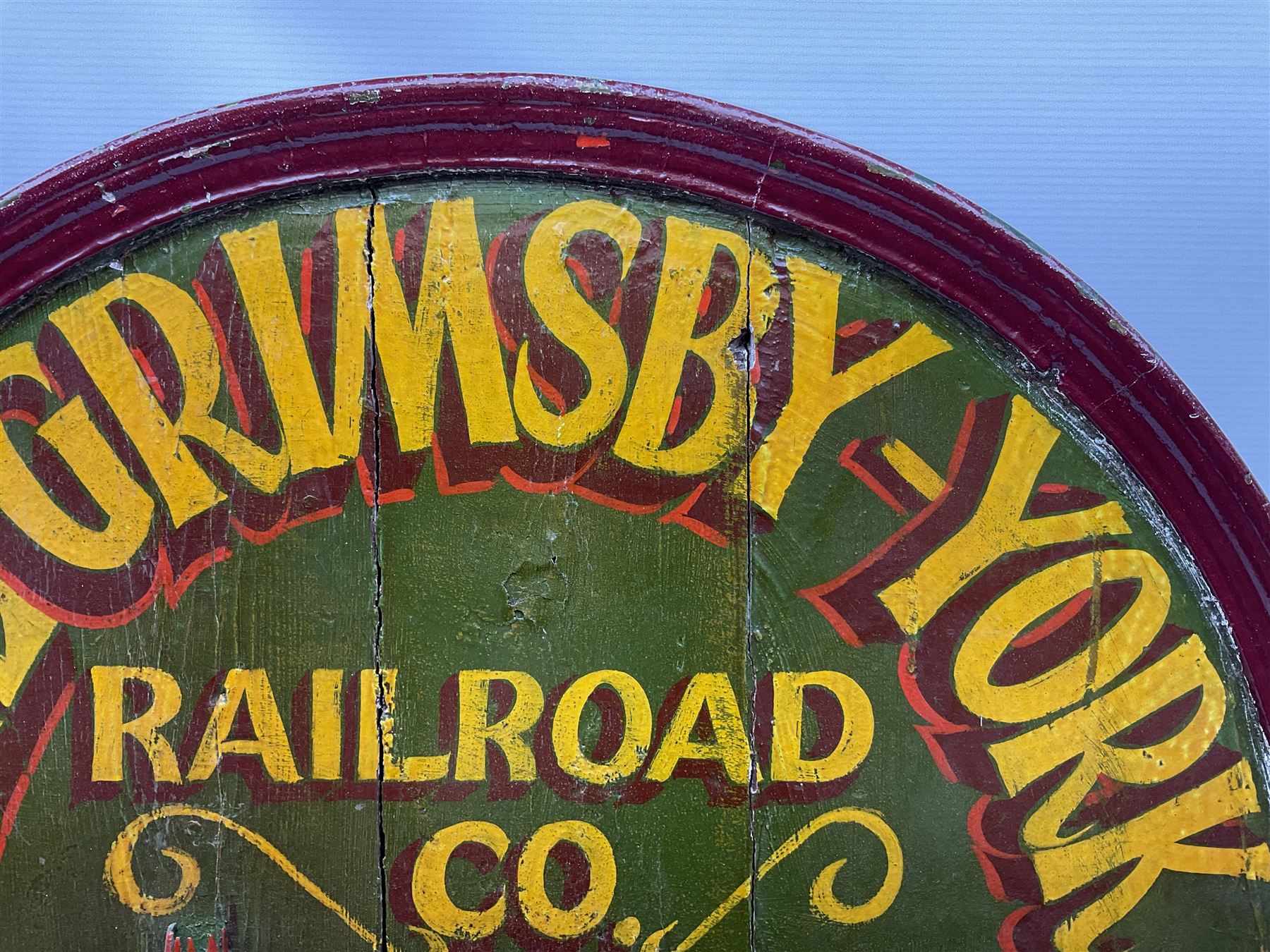 `The Grimsby-York Railroad Co.` painted wooden railway advertising sign 20th century, of planked construction with arched top and moulded border, decorated with an applied wood and metal image of an early steam locomotive in relief, the surrounding wording reading `The Grimsby-York Railroad Co., Fast Dispatch by Rail from Fish Curing Houses of Grimsby & Hull, Est. 1873, Daily Connections to Billingsgate`, 89 x 71cm
