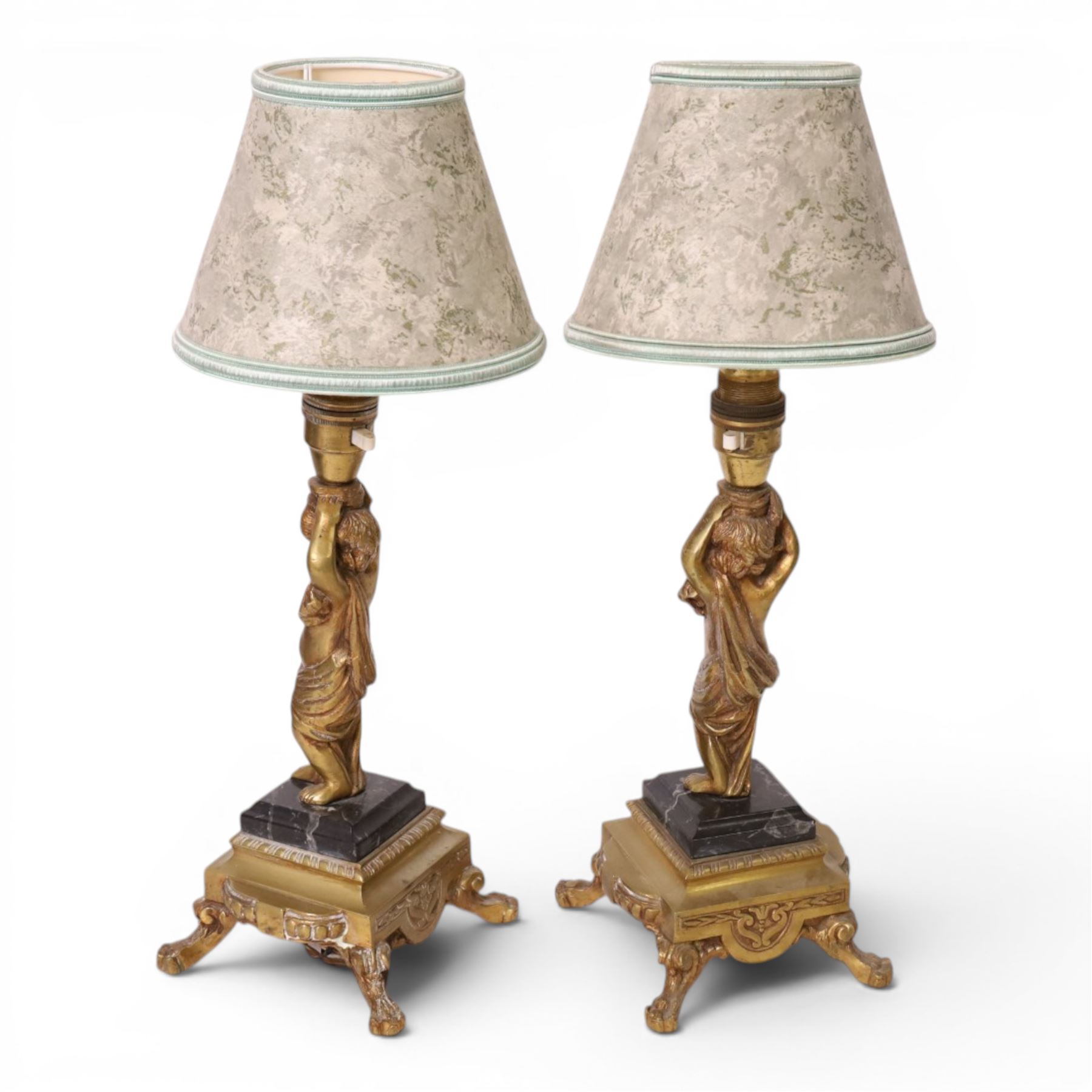 Pair of brass table lamps, the central column modeled as a putti upon a square marble base raised upon four claw feet, H29cm