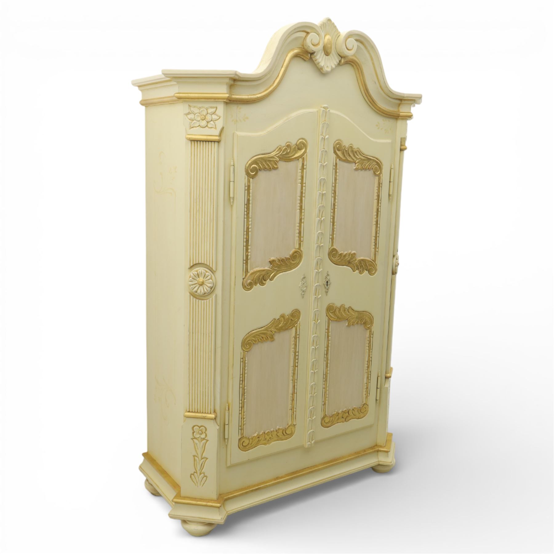 20th century French white and parcel gilt painted armoire, the shaped and scroll moulded cornice centred with a stylised foliate, the double doors with raised panel reserves applied with gilt foliate scrollwork, flanked by fluted pilasters with floral capitals, opening to a fitted interior with shelving and hanging space, raised on a moulded plinth on squat bun feet